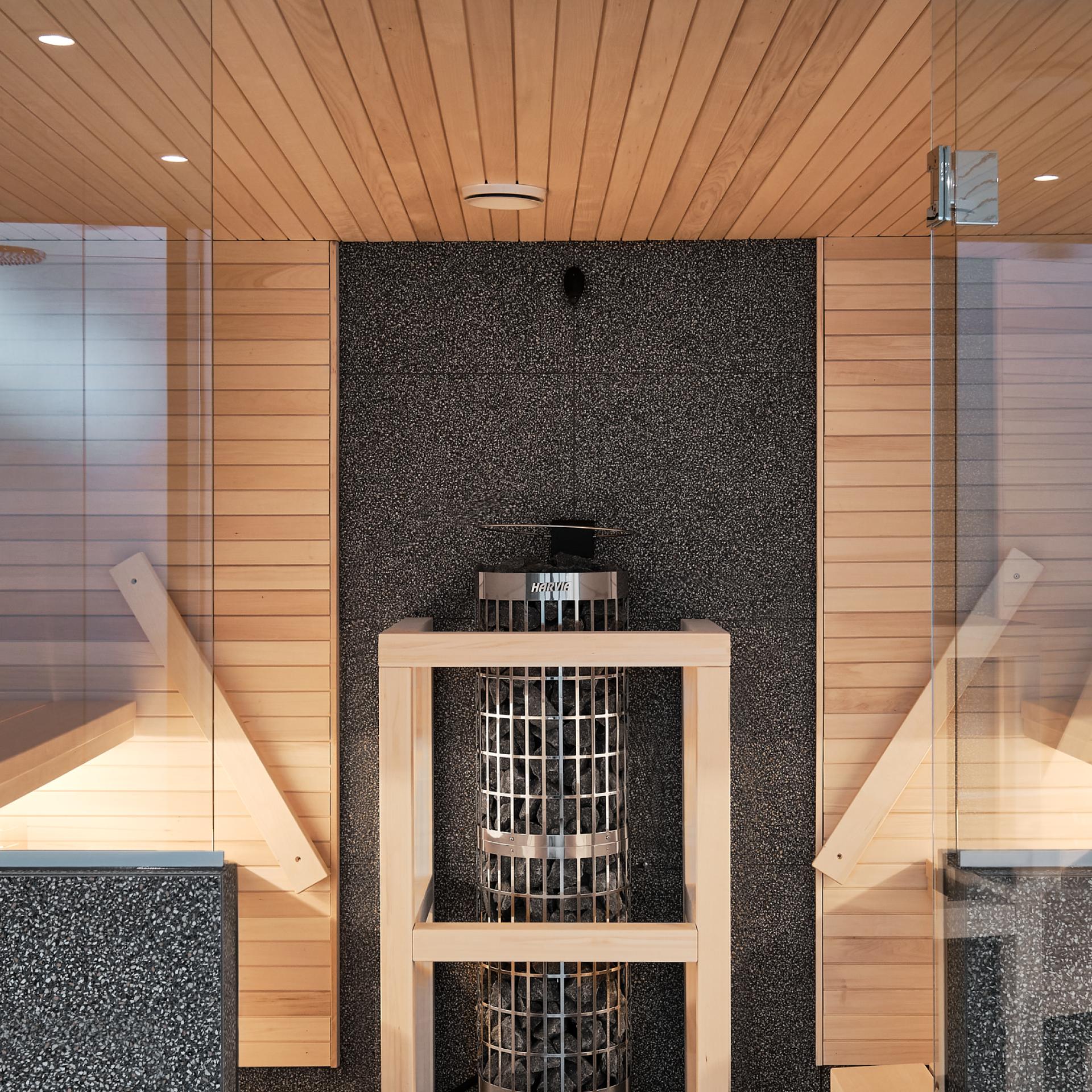 Moderni sauna, jossa on vaaleat puupenkit, keskellä kiuas ja tummat kiviseinät, mikä luo lämpimän ja kutsuvan tunnelman.