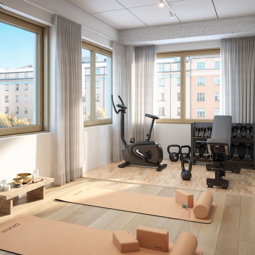 Kuntoilutila, jossa kuntopyörä, joogamattoja ja käsipainoja